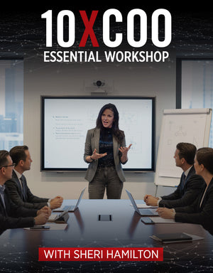 Sheri Hamilton leading an executive-level training session, standing at the front of a conference room while speaking to a group of business professionals seated around a table during the 10X COO Essential Workshop.